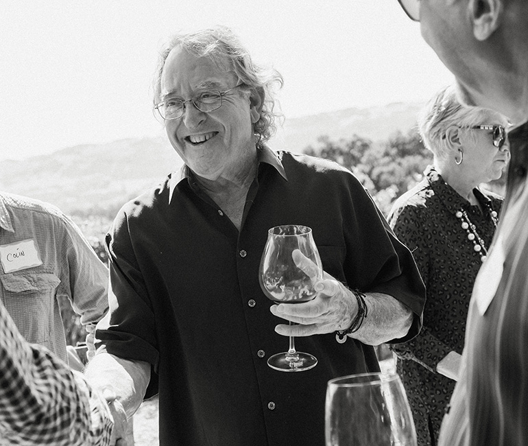 Brion Wise holding a glass of wine and shaking hands