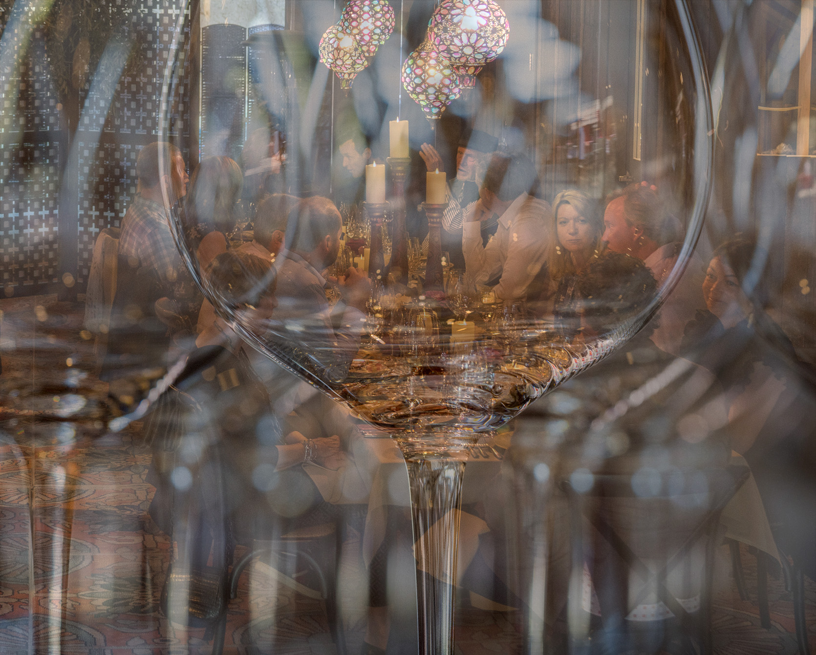 Dinner party seen through wine glasses on a shelf