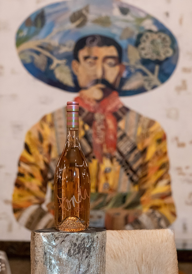 Bottle of rosé in from of a painting of a man with a sombrero
